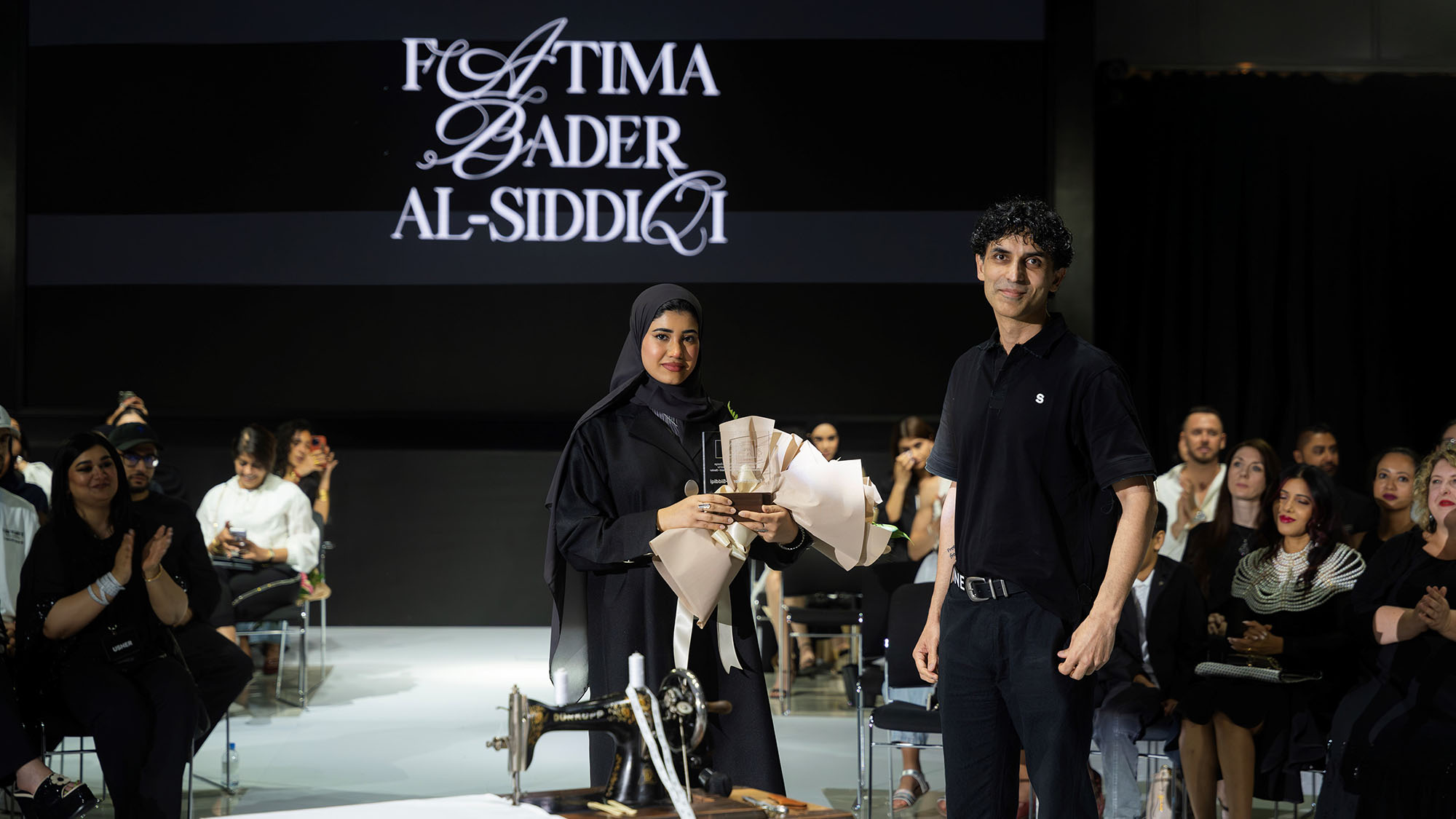 Fatima Bader Al Siddiqi won two awards : the Golden Needle Award for Most Outstanding Senior and the Outstanding Academic Achievement Award for a senior student from the graduating fashion design class . She's seen here receiving one of the awards from Professor Ali Khan 