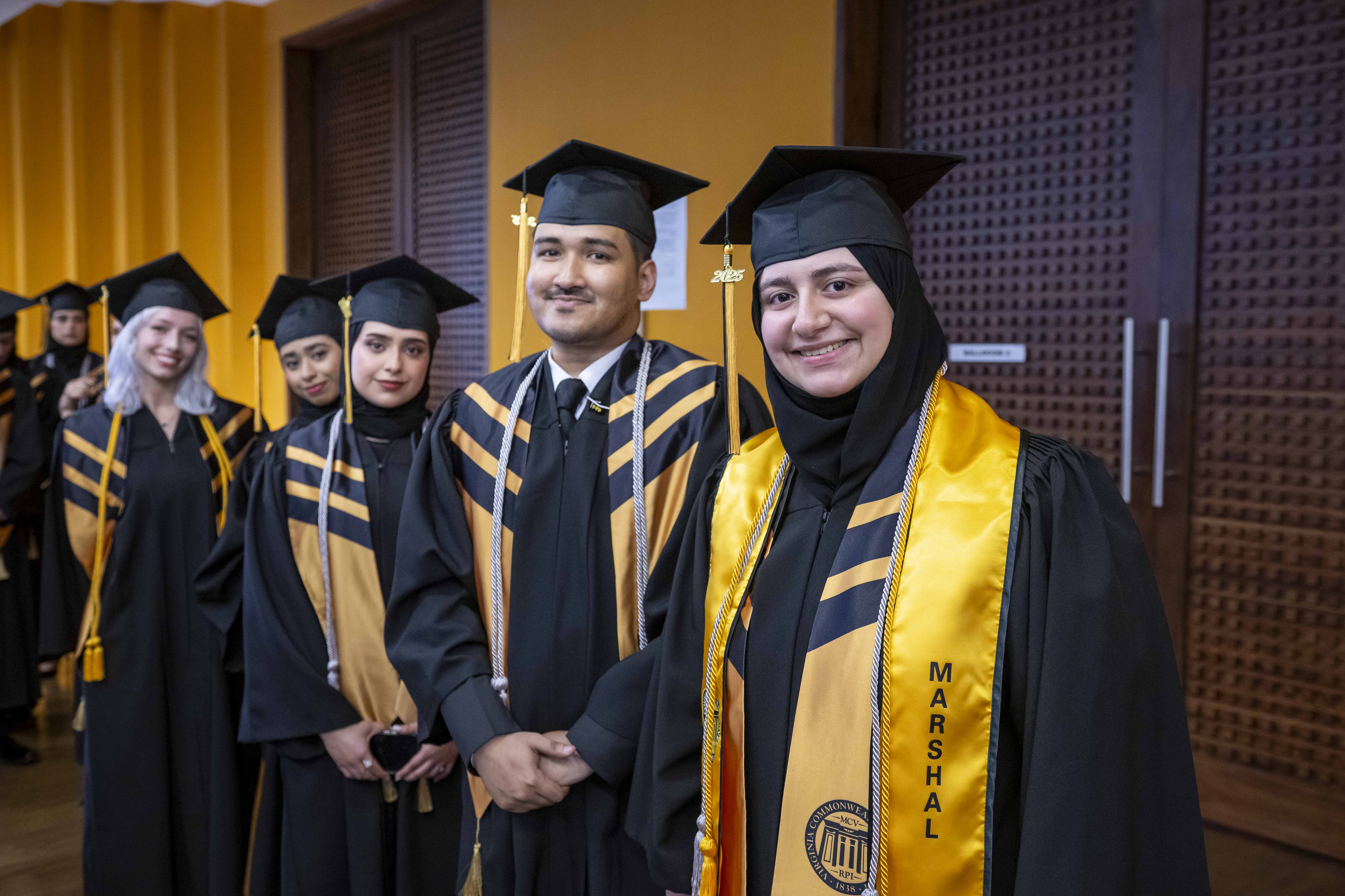 Students in regalia standing next to each other in line.